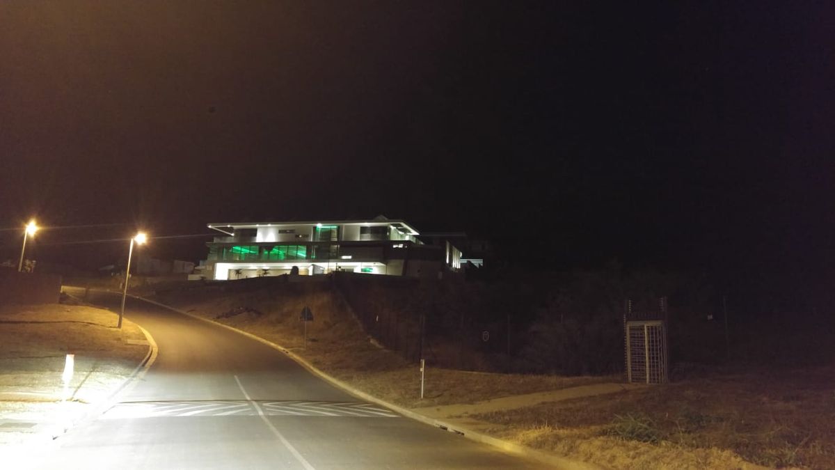 Street lights along a road leading to a lit home at night