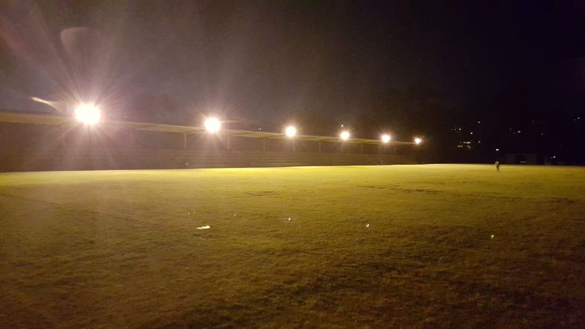 A row of floodlights lighting a sports field at night